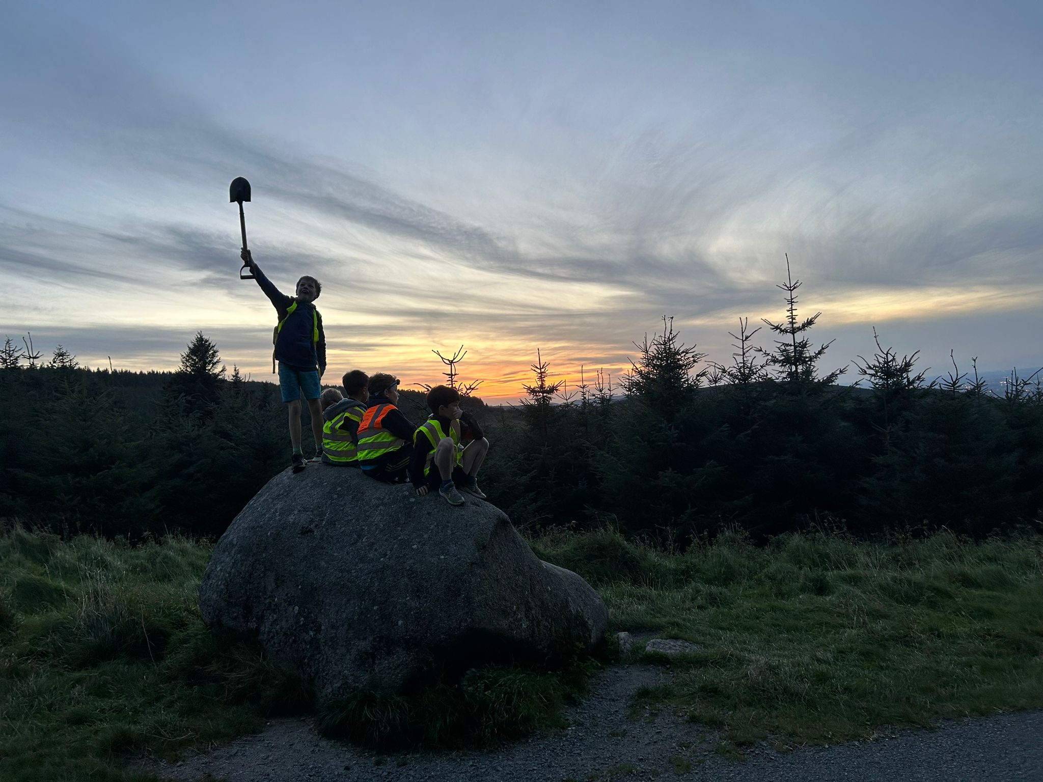 Scout silhouetted on a boulder at sunset in the Dublin hills