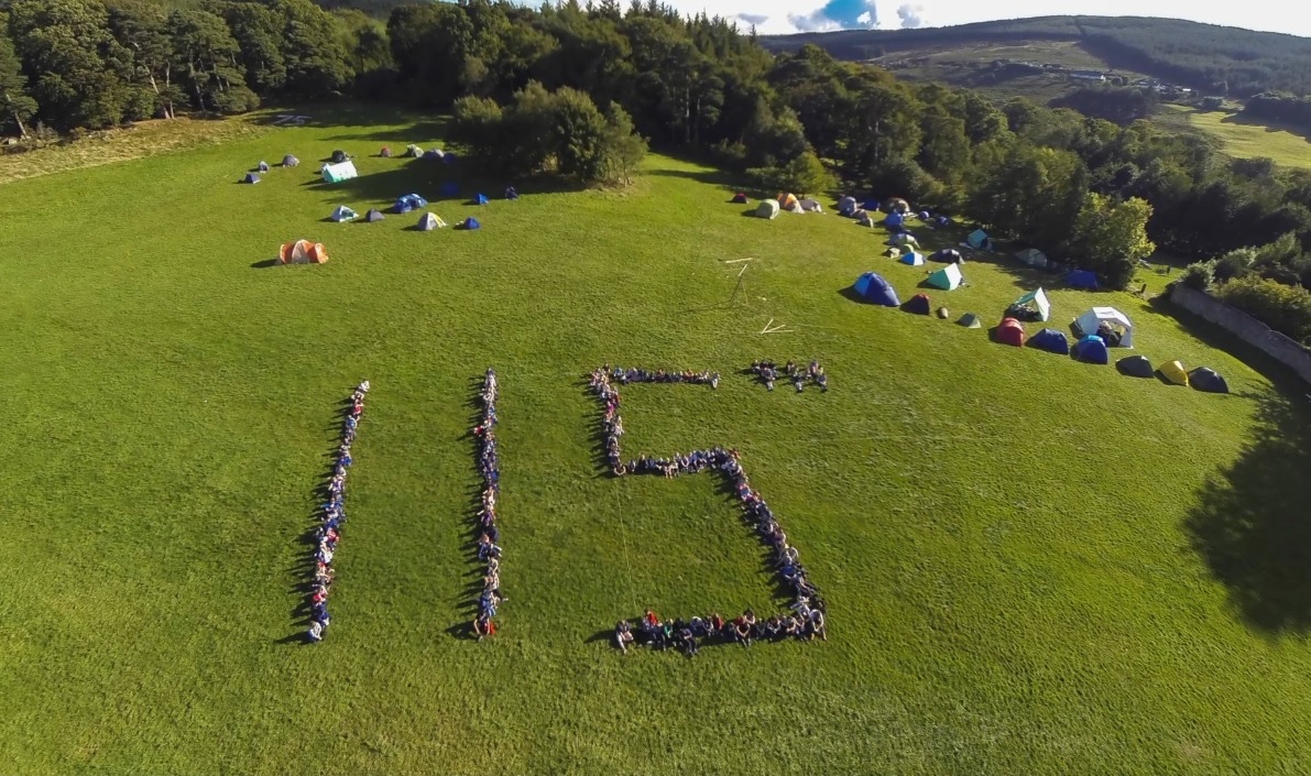 Aerial view of 115th Ballinteer members forming the number 115 on a campsite field, with tents scattered across the hillside — Group Camp 2013