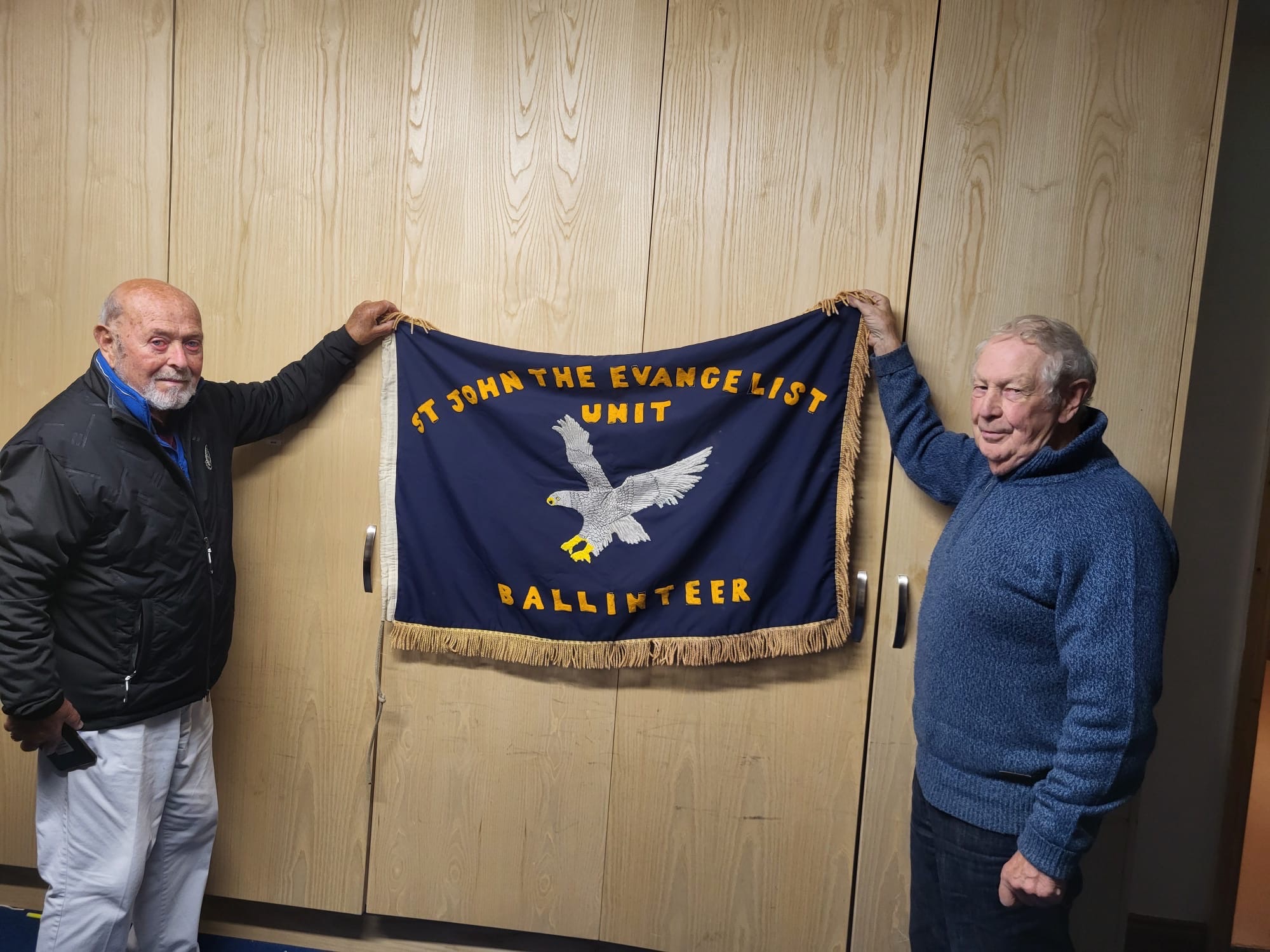 Don Kerrigan and Peter Curran holding the original 115th Ballinteer flag at the 50th anniversary